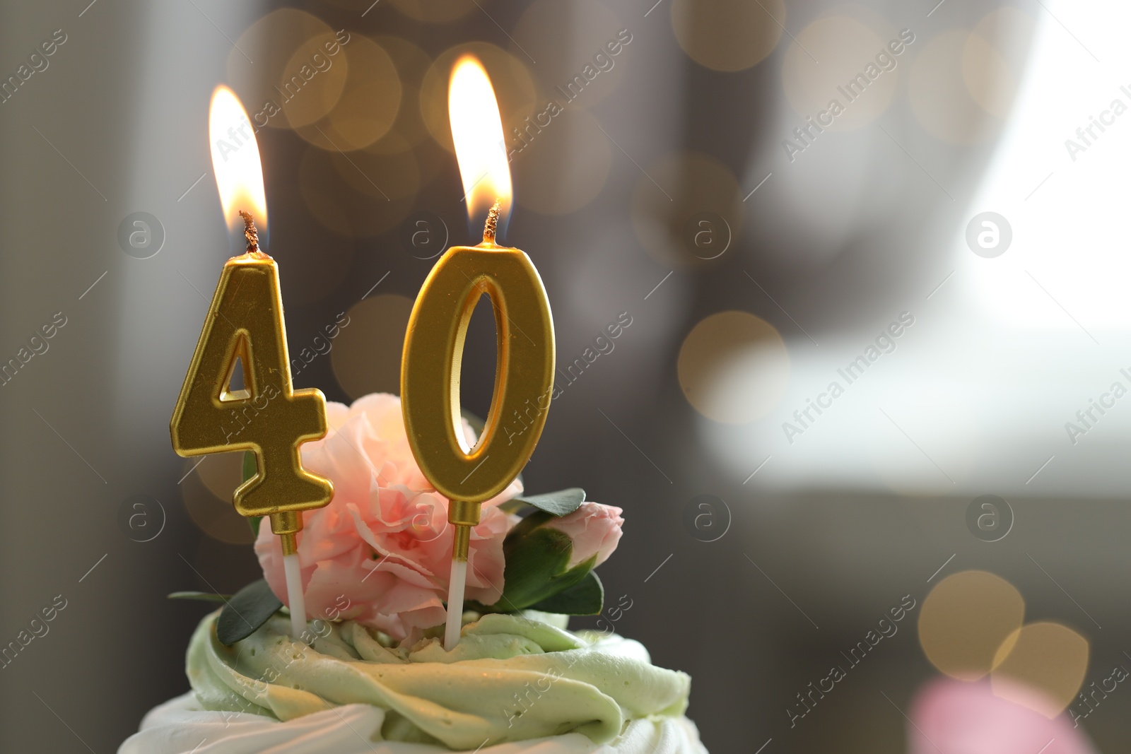 Photo of 40th birthday. Tasty cupcake with burning number shaped candles on blurred background with lights, space for text. Bokeh effect