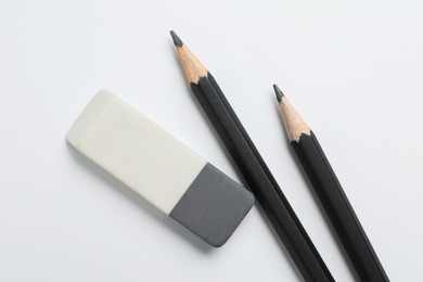 Photo of Eraser and pencils on white background, flat lay