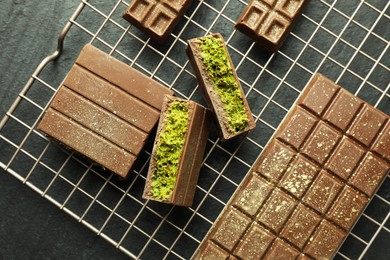 Photo of Delicious Dubai chocolate bars with pistachios and knafeh on black table, top view