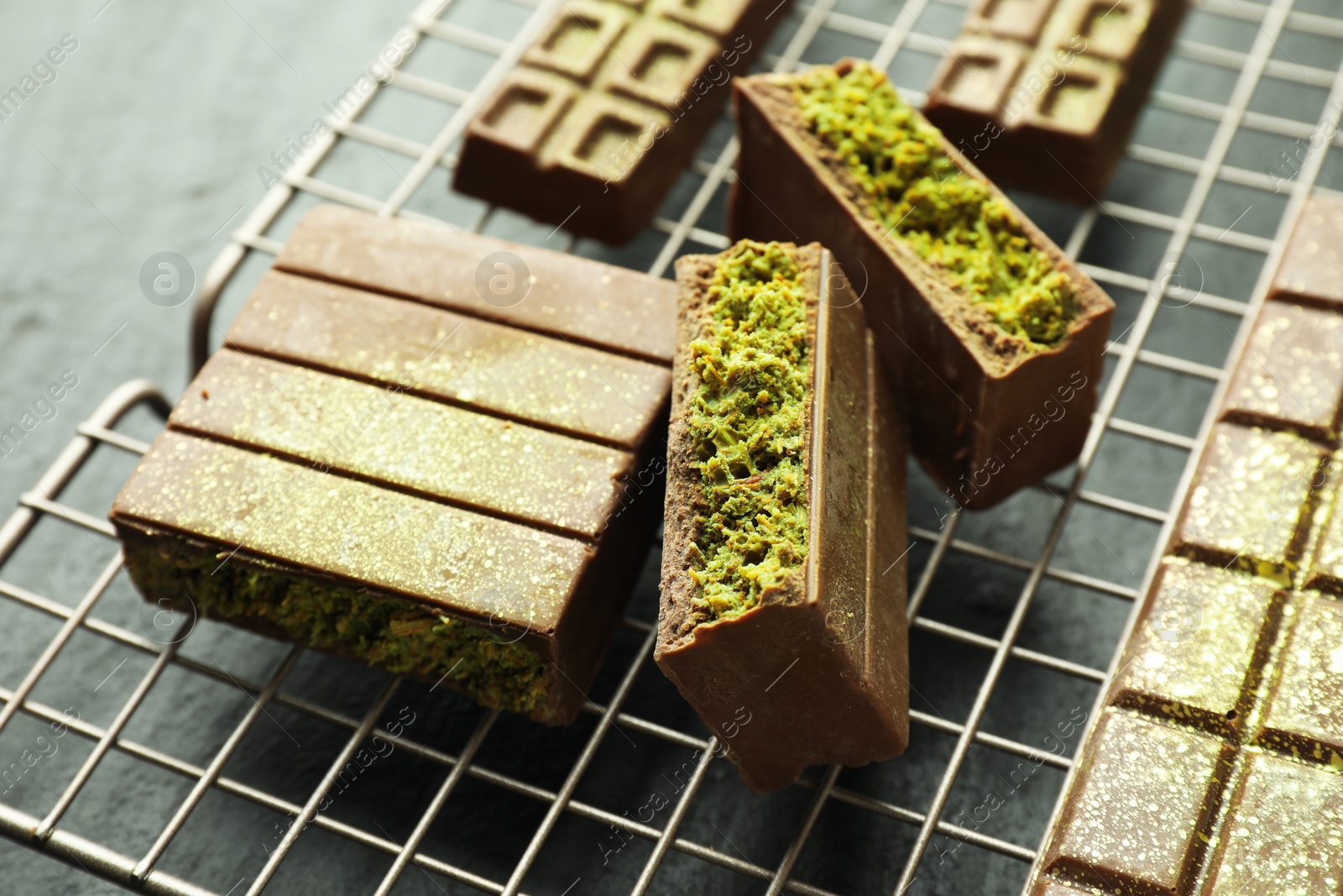Photo of Pieces of delicious Dubai chocolate bars with pistachios and knafeh on grey table, closeup