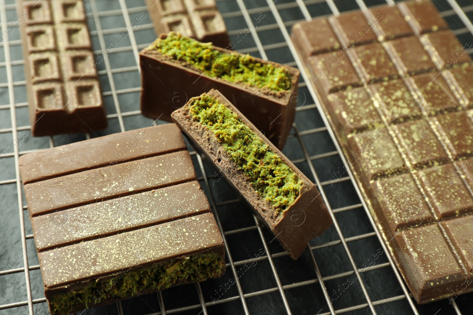 Photo of Pieces of delicious Dubai chocolate bars with pistachios and knafeh on grey table, closeup