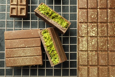 Photo of Delicious Dubai chocolate bars with pistachios and knafeh on black table, top view