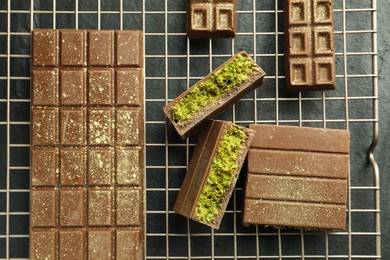 Photo of Delicious Dubai chocolate bars with pistachios and knafeh on black table, top view