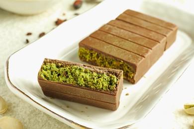 Photo of Pieces of delicious Dubai chocolate with pistachios and knafeh on table, closeup