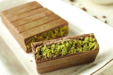 Photo of Pieces of delicious Dubai chocolate with pistachios and knafeh on table, closeup