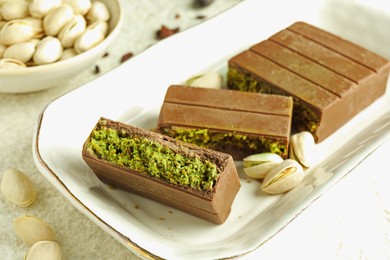 Photo of Pieces of delicious Dubai chocolate with pistachios and knafeh on table, closeup