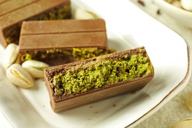 Photo of Pieces of delicious Dubai chocolate with pistachios and knafeh on table, closeup