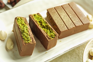 Photo of Pieces of delicious Dubai chocolate with pistachios and knafeh on table, closeup