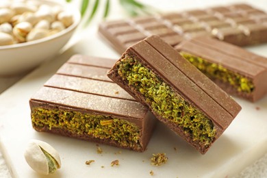 Photo of Pieces of delicious Dubai chocolate with pistachios and knafeh on table, closeup