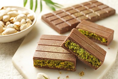 Photo of Pieces of delicious Dubai chocolate with pistachios and knafeh on table, closeup