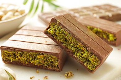 Photo of Pieces of delicious Dubai chocolate with pistachios and knafeh on table, closeup