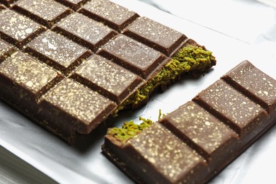 Photo of Delicious Dubai chocolate with pistachios and knafeh on table, closeup