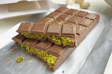 Photo of Delicious Dubai chocolate with pistachios and knafeh on table, closeup