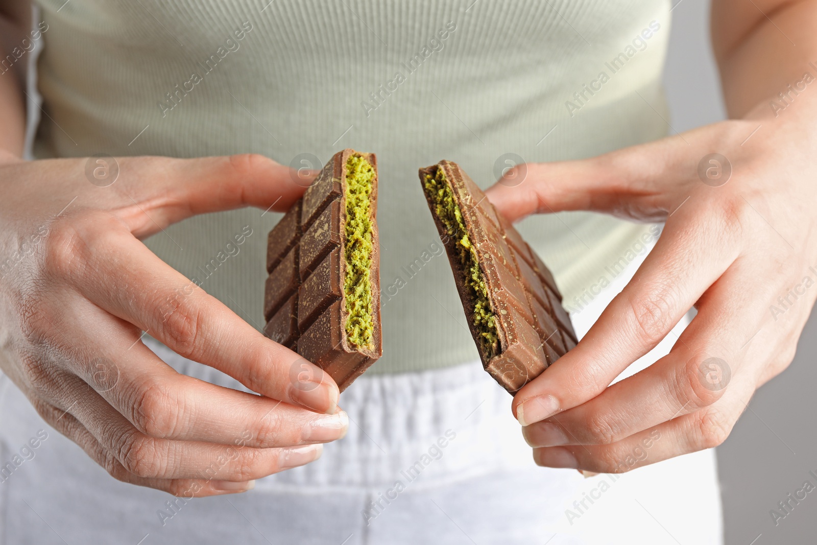 Photo of Woman holding pieces of delicious Dubai chocolate with pistachios and knafeh, closeup