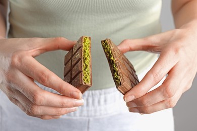 Woman holding pieces of delicious Dubai chocolate with pistachios and knafeh, closeup