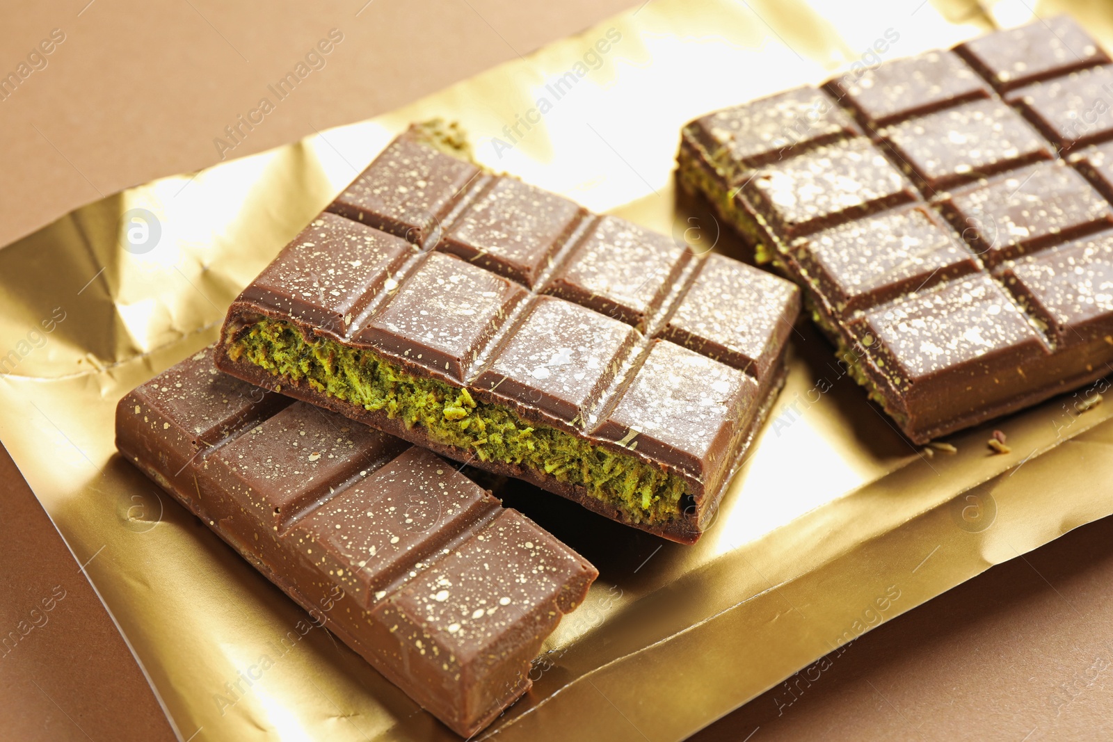 Pieces of delicious Dubai chocolate with pistachios and knafeh on dark beige background, closeup Photo of Pieces of delicious Dubai chocolate with pistachios and knafeh on dark beige background, closeup