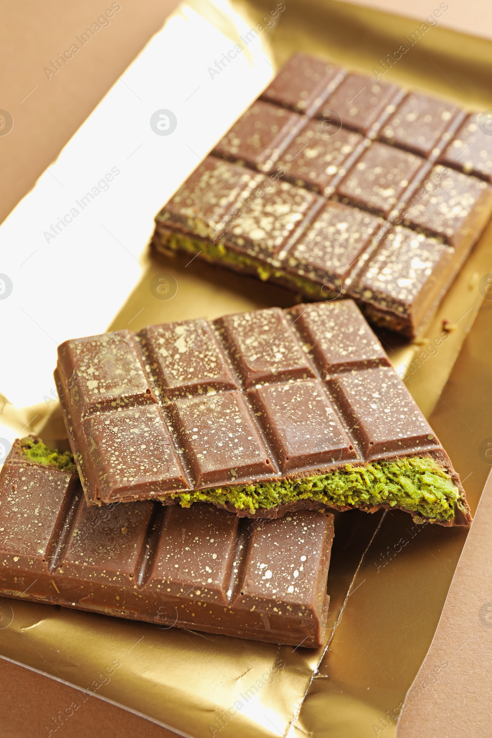 Pieces of delicious Dubai chocolate with pistachios and knafeh on dark beige background, closeup Photo of Pieces of delicious Dubai chocolate with pistachios and knafeh on dark beige background, closeup