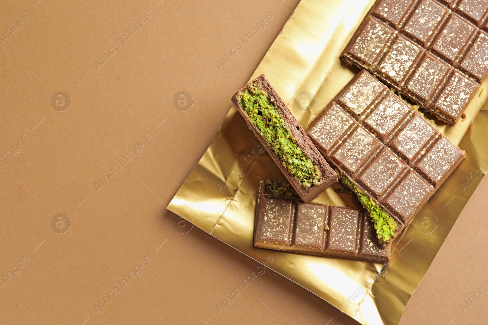 Pieces of delicious Dubai chocolate with pistachios and knafeh on dark beige background, top view. Space for text Photo of Pieces of delicious Dubai chocolate with pistachios and knafeh on dark beige background, top view. Space for text