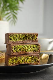 Photo of Pieces of delicious Dubai chocolate with pistachios and knafeh on table, closeup