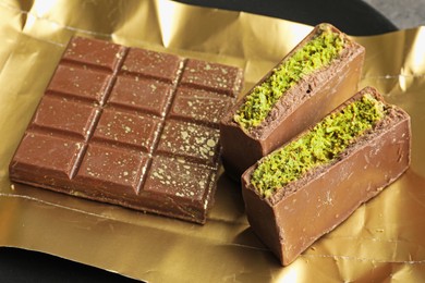 Photo of Pieces of delicious Dubai chocolate with pistachios and knafeh on table, closeup