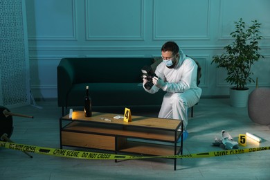 Photo of Forensic expert with camera taking photo of evidences at crime scene indoors