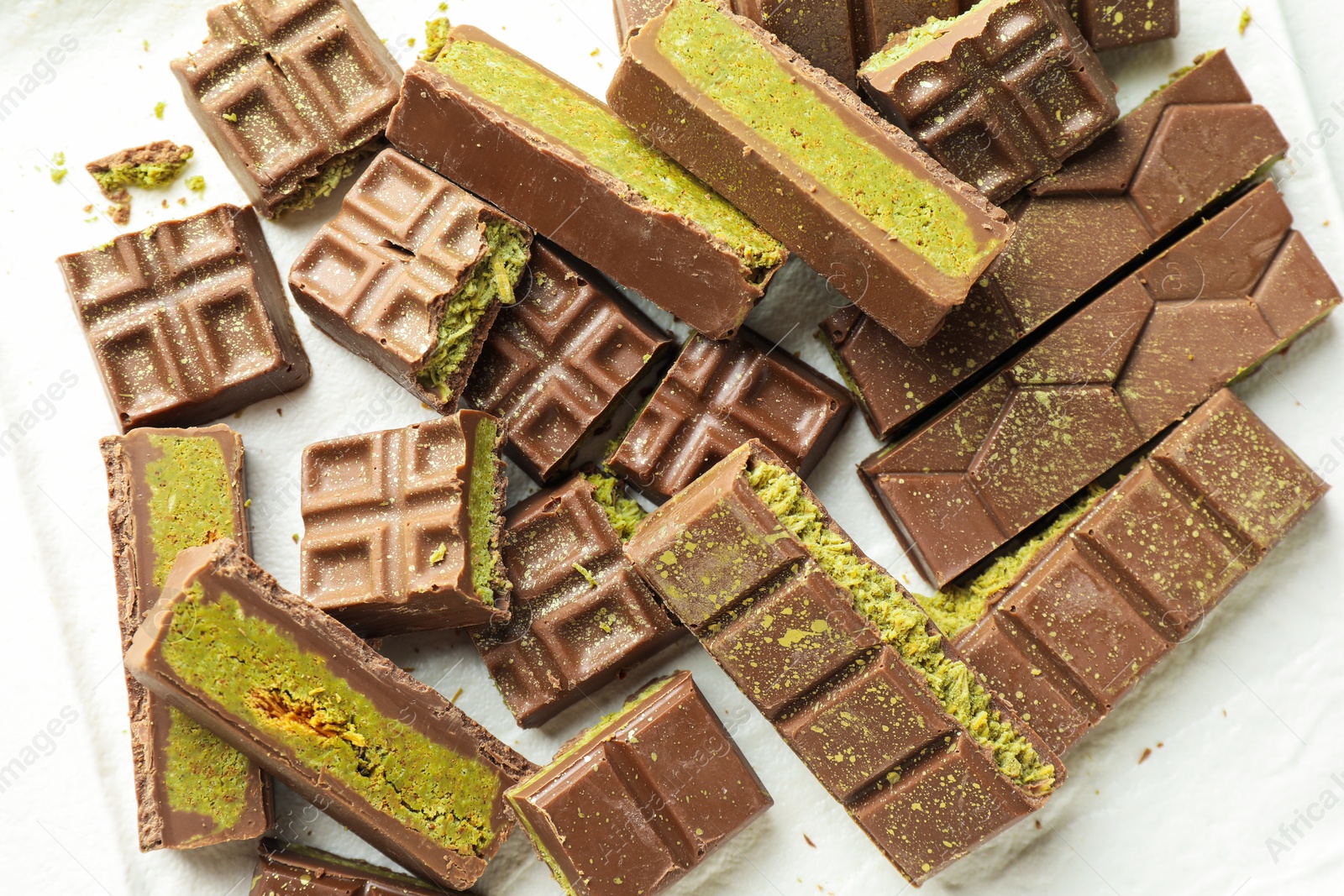 Pieces of tasty Dubai chocolate with pistachios and knafeh on plate, top view Photo of Pieces of tasty Dubai chocolate with pistachios and knafeh on plate, top view