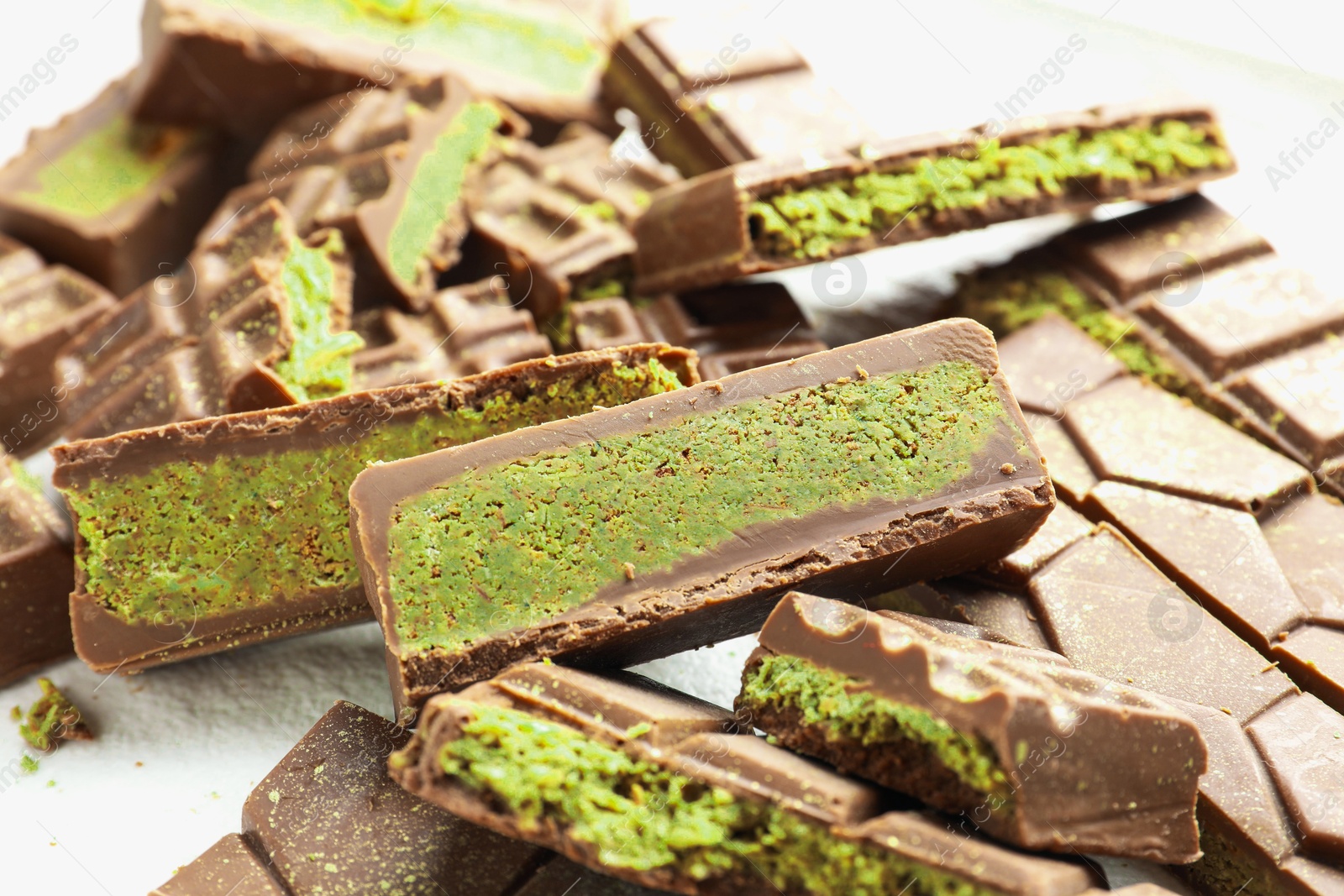 Pieces of tasty Dubai chocolate with pistachios and knafeh on white table, closeup Photo of Pieces of tasty Dubai chocolate with pistachios and knafeh on white table, closeup