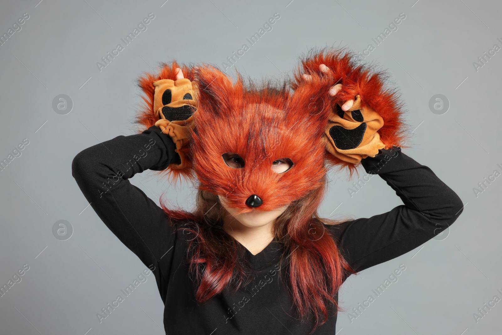 Photo of Quadrobics. Girl wearing fox mask and gloves on grey background