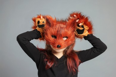 Quadrobics. Girl wearing fox mask and gloves on grey background