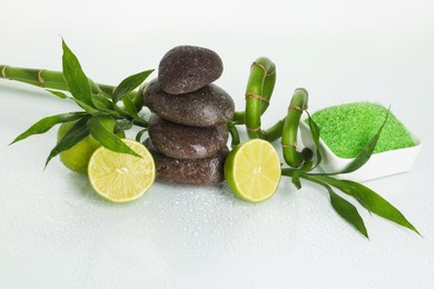 Photo of Spa composition with fresh limes, sea salt, massage stones and bamboo on wet surface