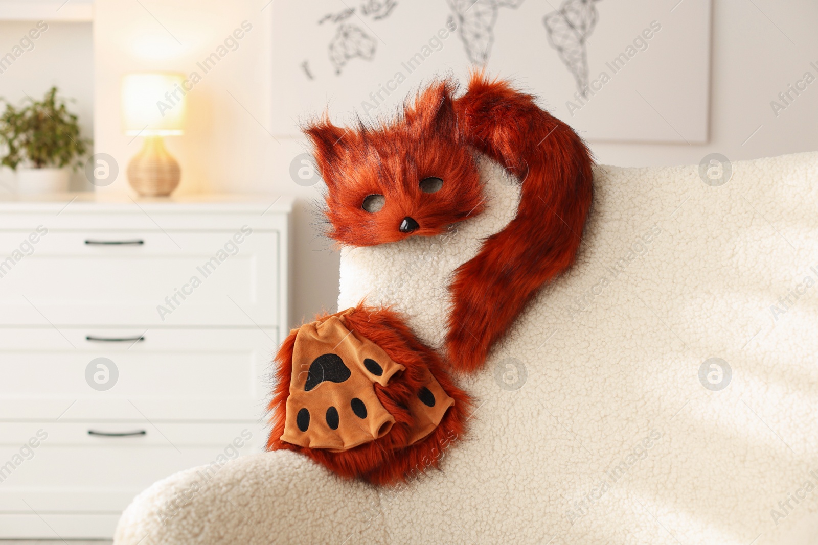 Photo of Quadrobics. Fox mask, gloves and tail on armchair indoors, space for text