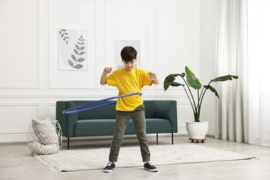 Photo of Boy exercising with hula hoop at home