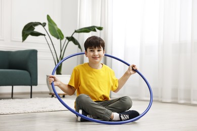 Boy with hula hoop on floor at home