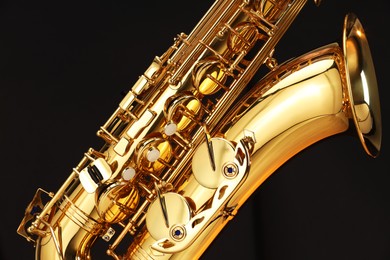 Photo of Jazz. One beautiful saxophone on black background, closeup