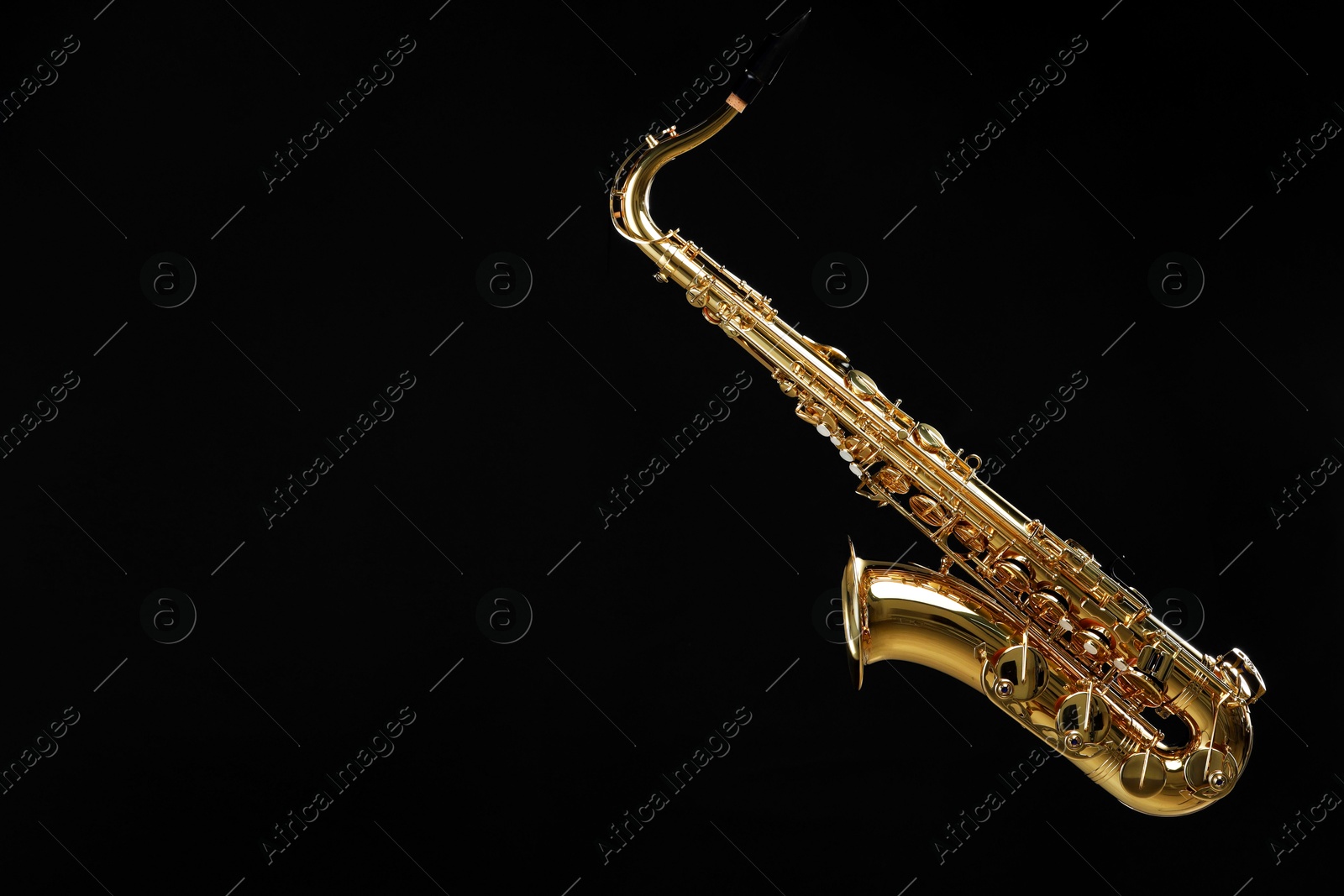 Photo of Jazz. One beautiful saxophone hanging from strap on black background, space for text