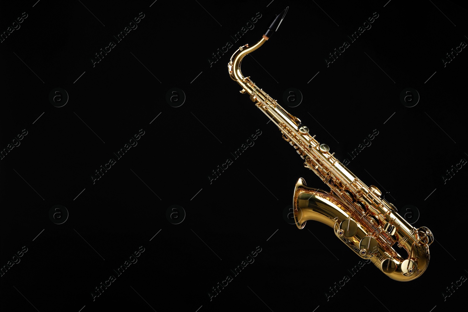 Photo of Jazz. One beautiful saxophone hanging from strap on black background, space for text