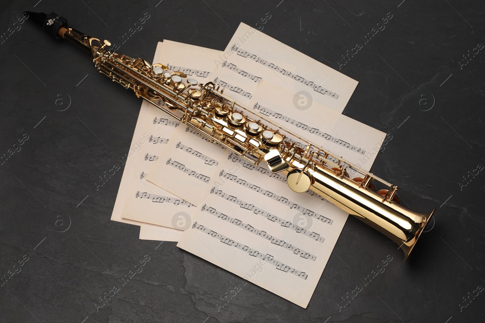 Photo of Jazz. Saxophone and music notes on black table, top view