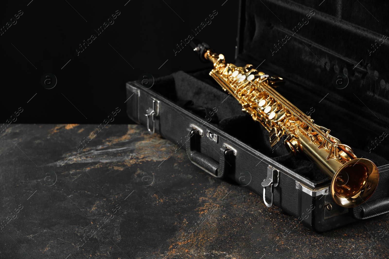 Photo of Jazz. Golden saxophone in case on black textured table, space for text