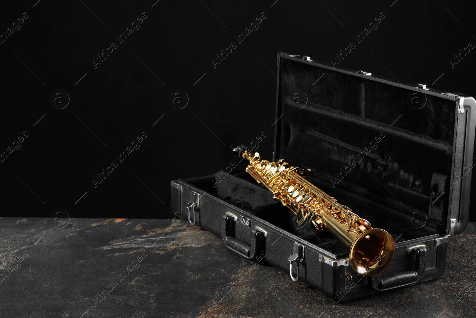 Photo of Jazz. Golden saxophone in case on black textured table, space for text