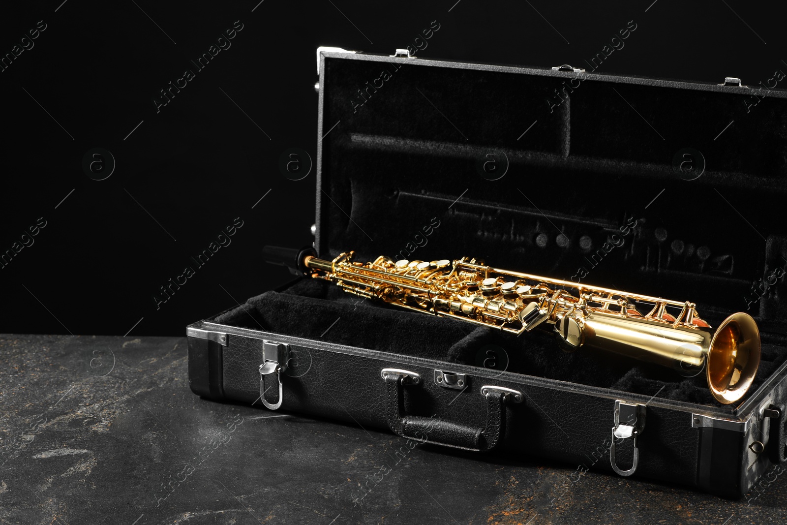 Photo of Jazz. Golden saxophone in case on black textured table, space for text