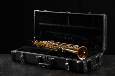 Photo of Jazz. Golden saxophone in case on black textured table