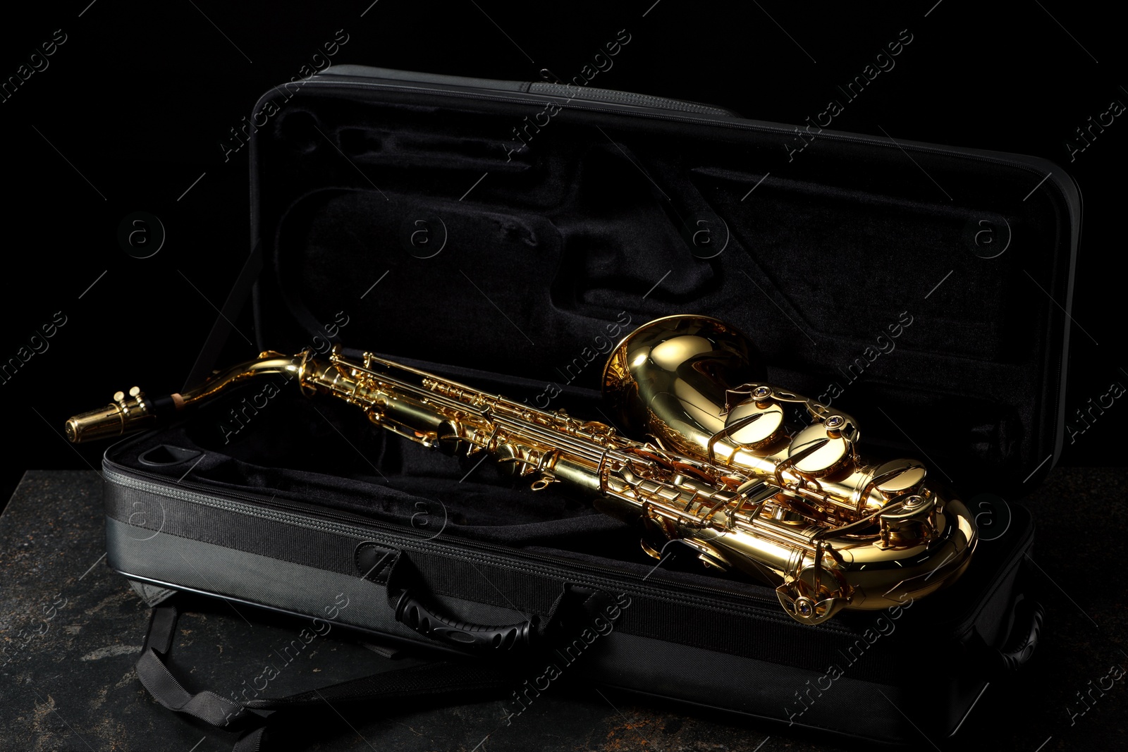 Photo of Jazz. Golden saxophone in case on black textured table