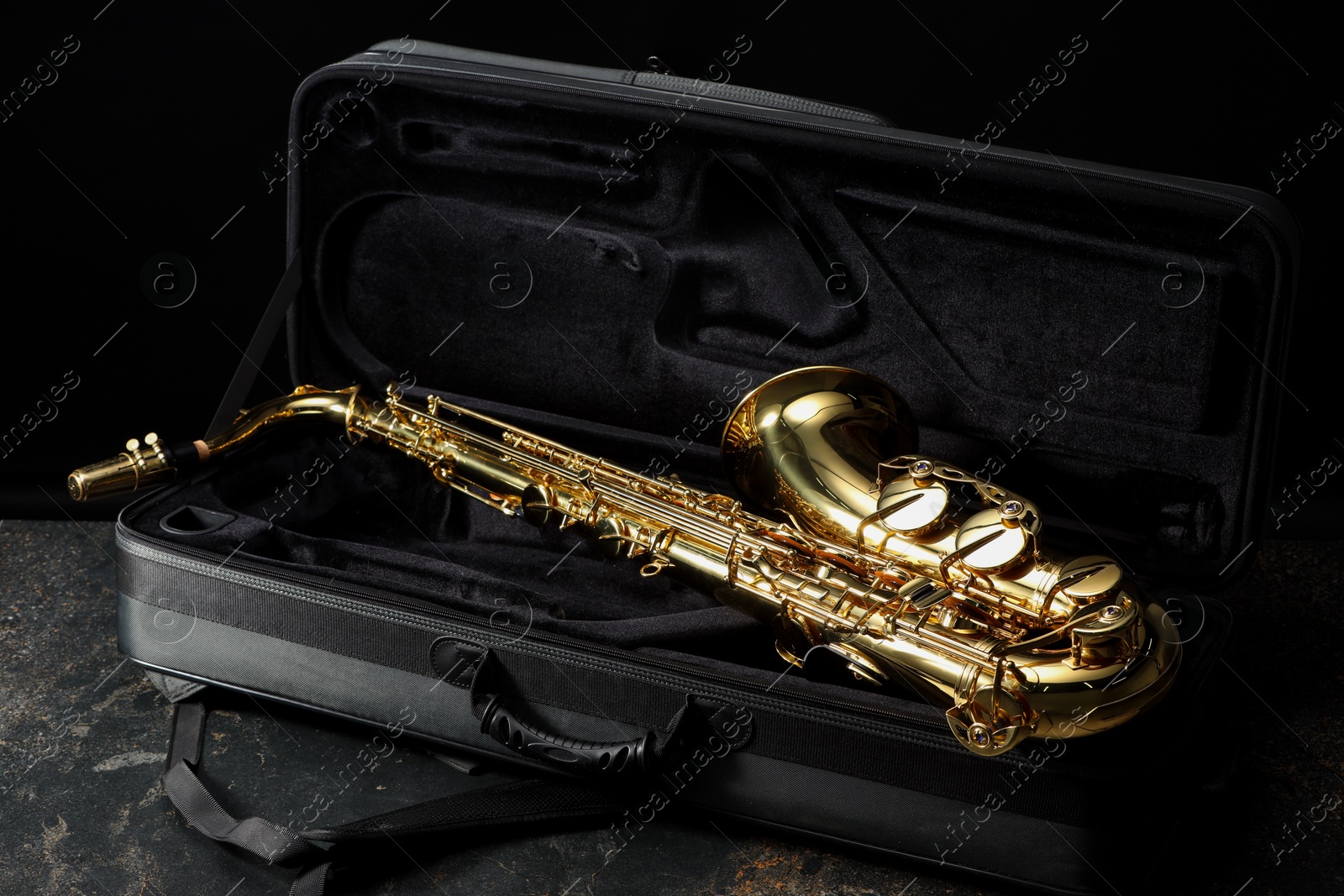 Photo of Jazz. Golden saxophone in case on black textured table