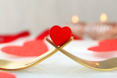 Photo of Romantic table setting for Valentine's day. Decorative heart between forks on white plate, closeup