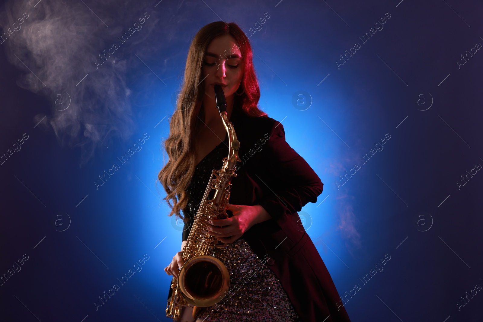 Photo of Professional musician playing saxophone on color background with smoke