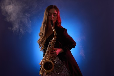 Photo of Professional musician playing saxophone on color background with smoke