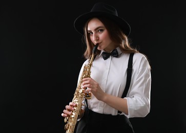 Photo of Musician playing soprano saxophone on dark background. Space for text