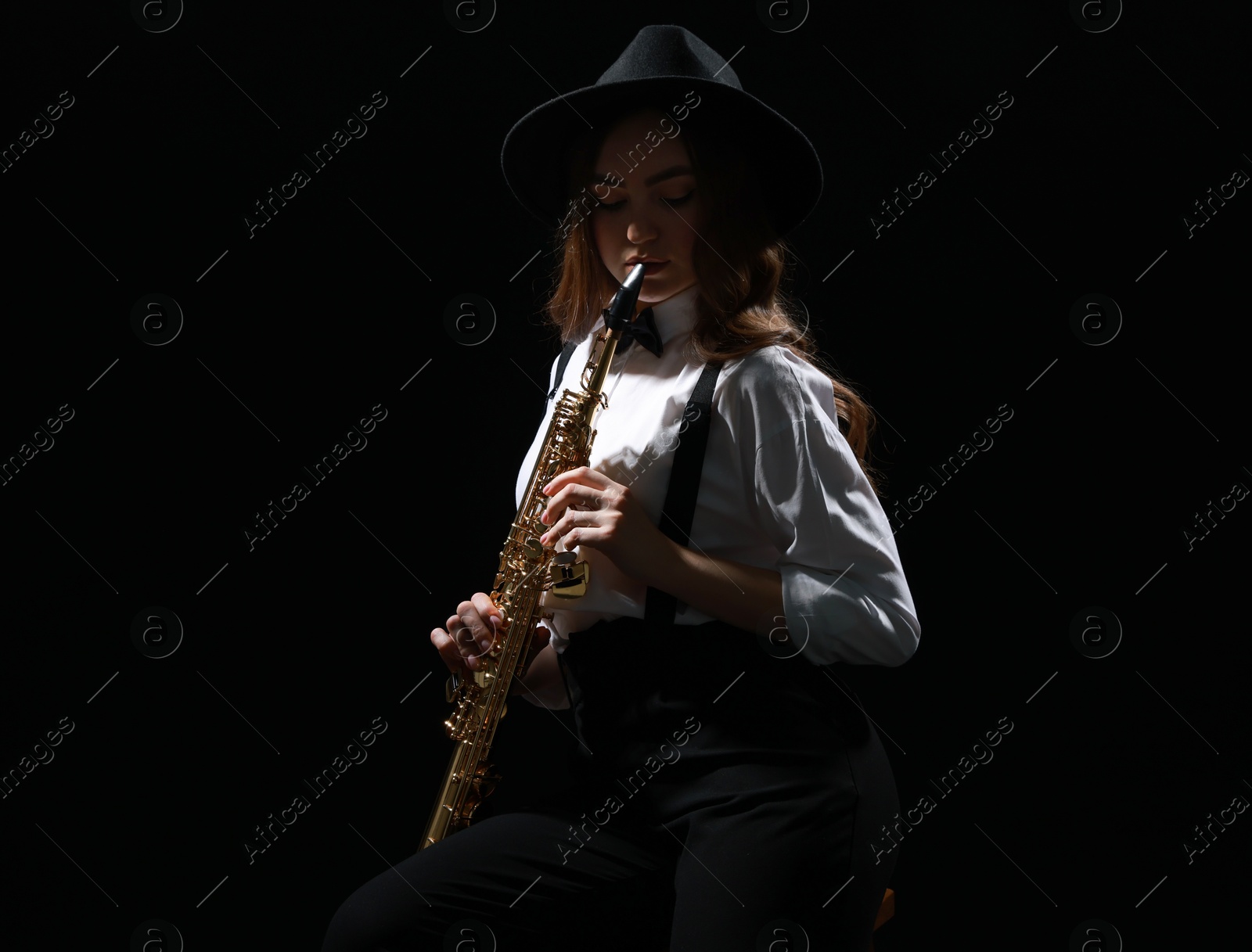 Photo of Musician playing soprano saxophone on dark background. Space for text