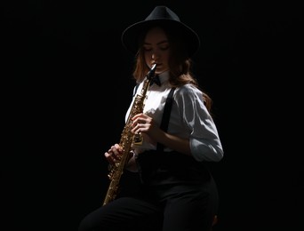 Photo of Musician playing soprano saxophone on dark background. Space for text