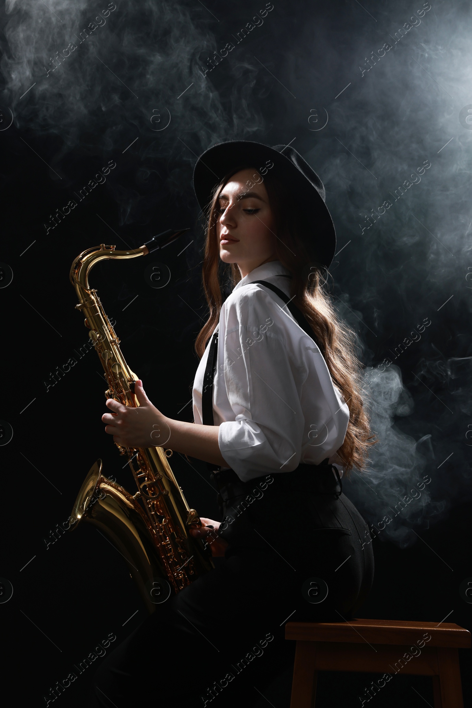 Photo of Professional musician playing saxophone on dark background with smoke